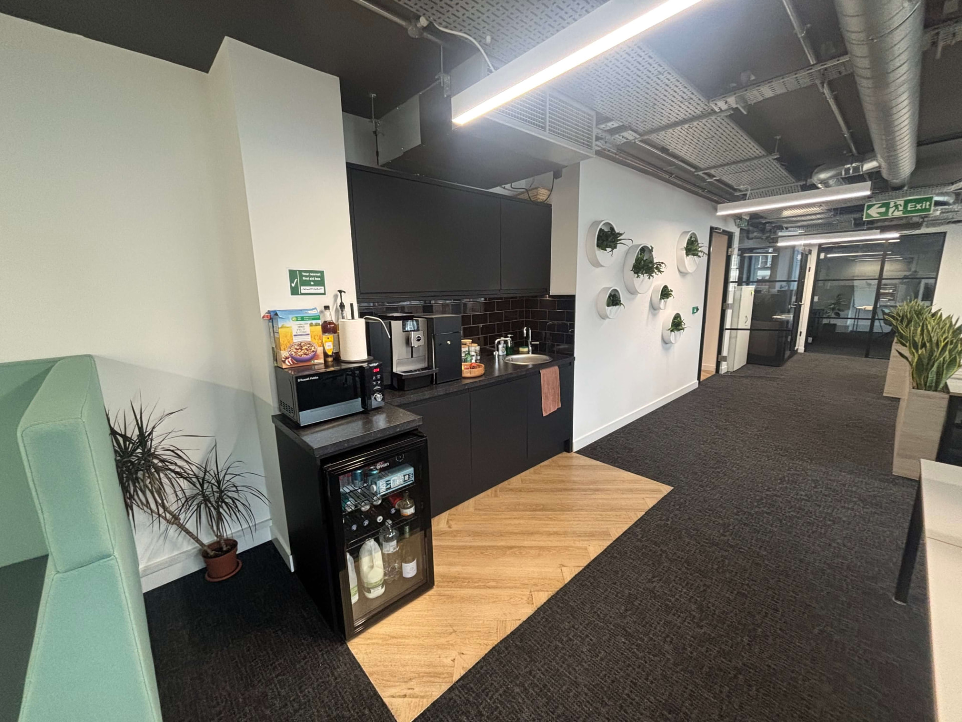 Office kitchen area with coffee station and wall-mounted planters